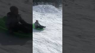 Boy goes downhill on sled then hits bump and flips awkwardly