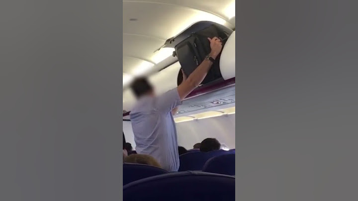 Man Struggles to Fit Small Carry On Bag in Overhead Bin