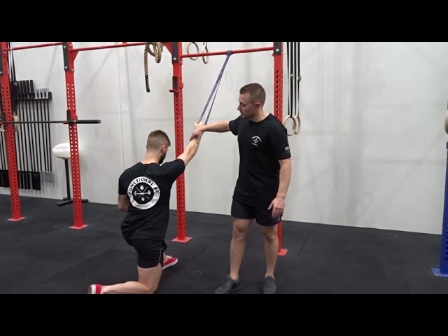 Person performing a half-kneeling single-arm lat pulldown with resistance band to strengthen lats and improve posture