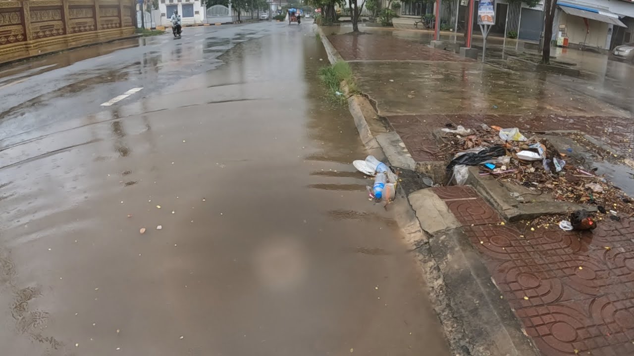 After heavy rain unclogging drain culvert rain water on the street road ...