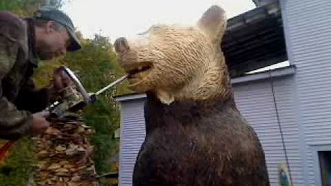 Barre Pinske carves teeth in a wooden bear