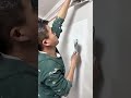 skimming the wall surface with a putty knife to cover imperfections and create a perfectly smooth
