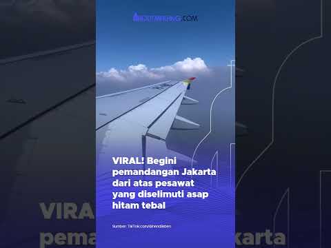 Penampakan polusi udara dengan asap hitam tebal di langit Jakarta yang terlihat dari atas pesawat.