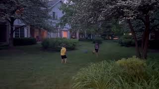 Boys play kickball on grass lawn in front of house then one gets hit on face by blue fall