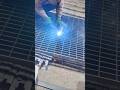 welding and joining a large grey metal grate structure using a handheld electric tool