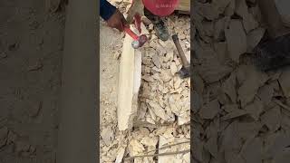 Pounding And Shaping A Large Stone Slab Using A Metal Hammer To Create Smooth Edges For Construction