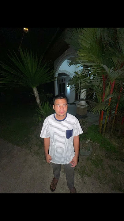 Gambar tersebut menampilkan seorang pria yang duduk di tepi pantai dengan latar belakang laut