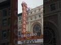Handheld shot showing famous Chicago Theatre marquee with flashing lights on North State Street