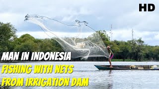 Man in Indonesia fishing with nets from irrigation dam