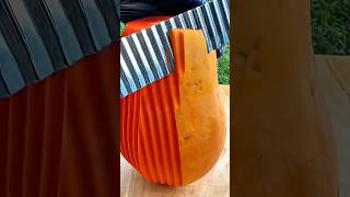 Slicing ripe papaya with wavy blade knife to create decorative ridges on bright orange flesh