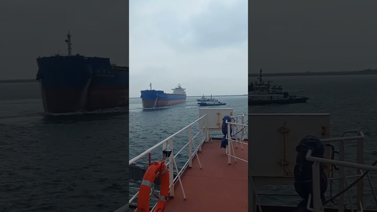 Two tagboats towing a large ship