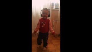 Маленькая девочка слушает в наушниках музыку и танцует