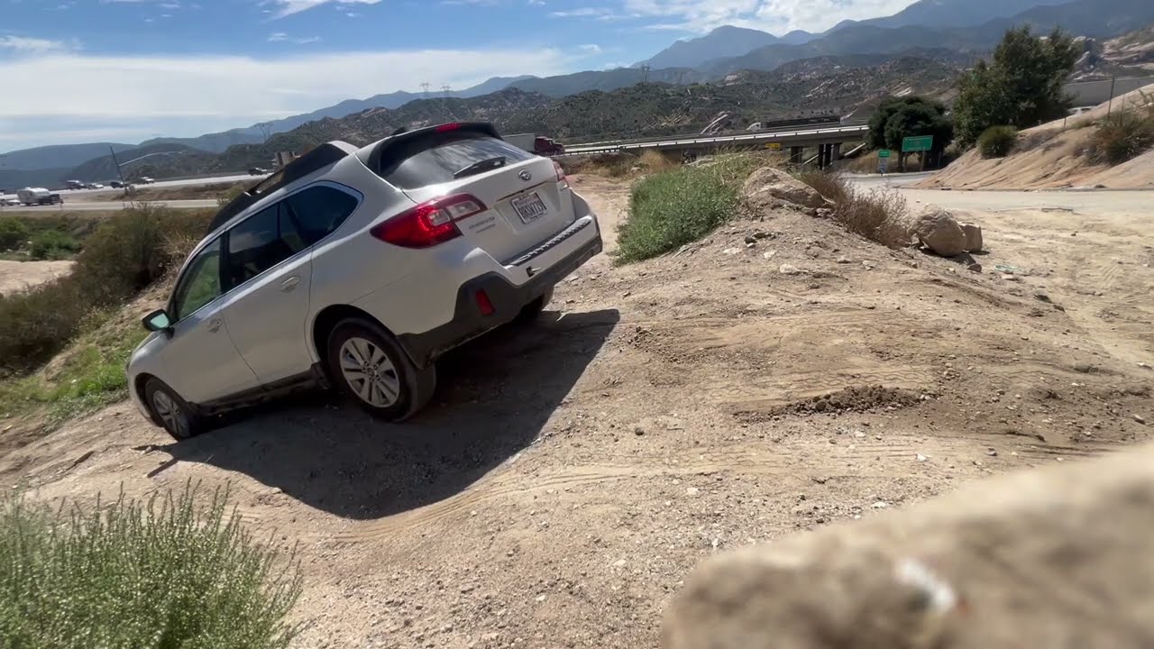 2018 Subaru Outback driving down a very steep uneven dirt hill filled ...