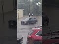 Person pushes car through flooded roadway