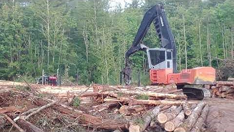 Hitachi log loader unloading log trailer off Kenworth