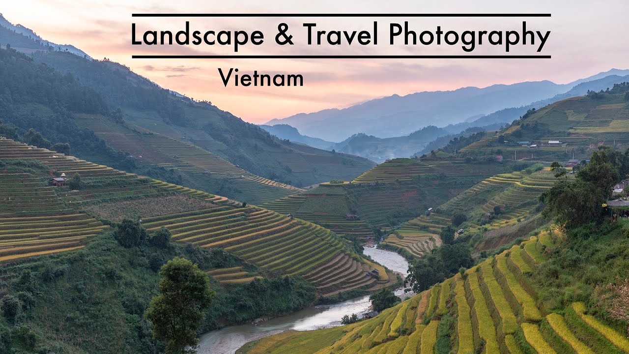 Lush terraced rice fields cascade down the rolling hills of Vietnam with a river weaving through the valley, set against a backdrop of misty mountains during sunset.