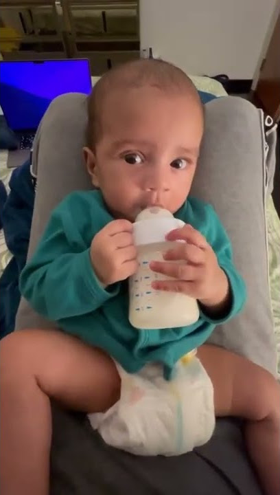 baby holding bottle and drinking milk