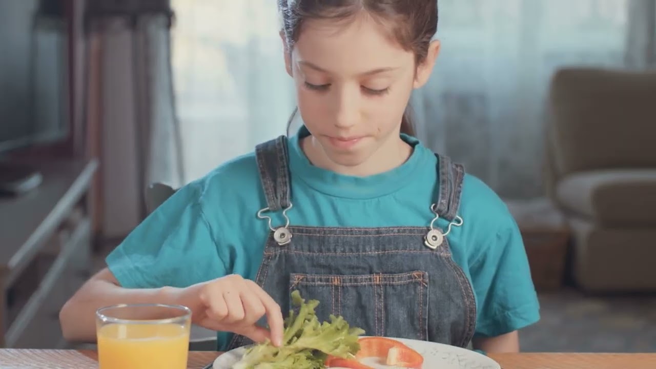 Video preview image of A picture of a girl looking at the lettuce on her plate; click to visit the ParentSquare post with the video