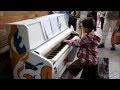 10 year old George Harliono playing street piano at a train station