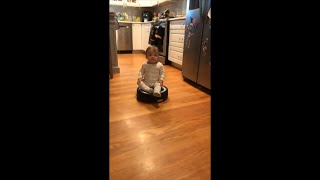Baby Riding on a Robot Vacuum as He Looks Around Then Tries to Touch Stickers and a Box