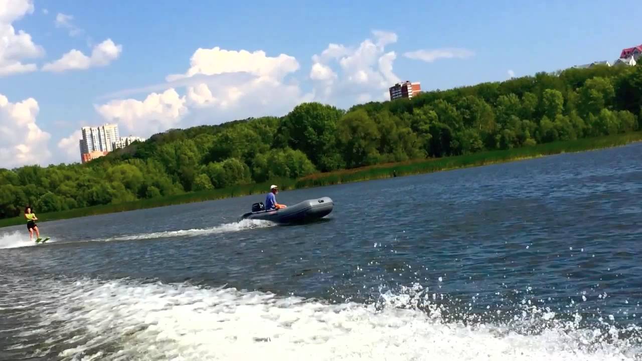 Резиновая лодка с минимальным движком продолжает тянуть лыжника ...