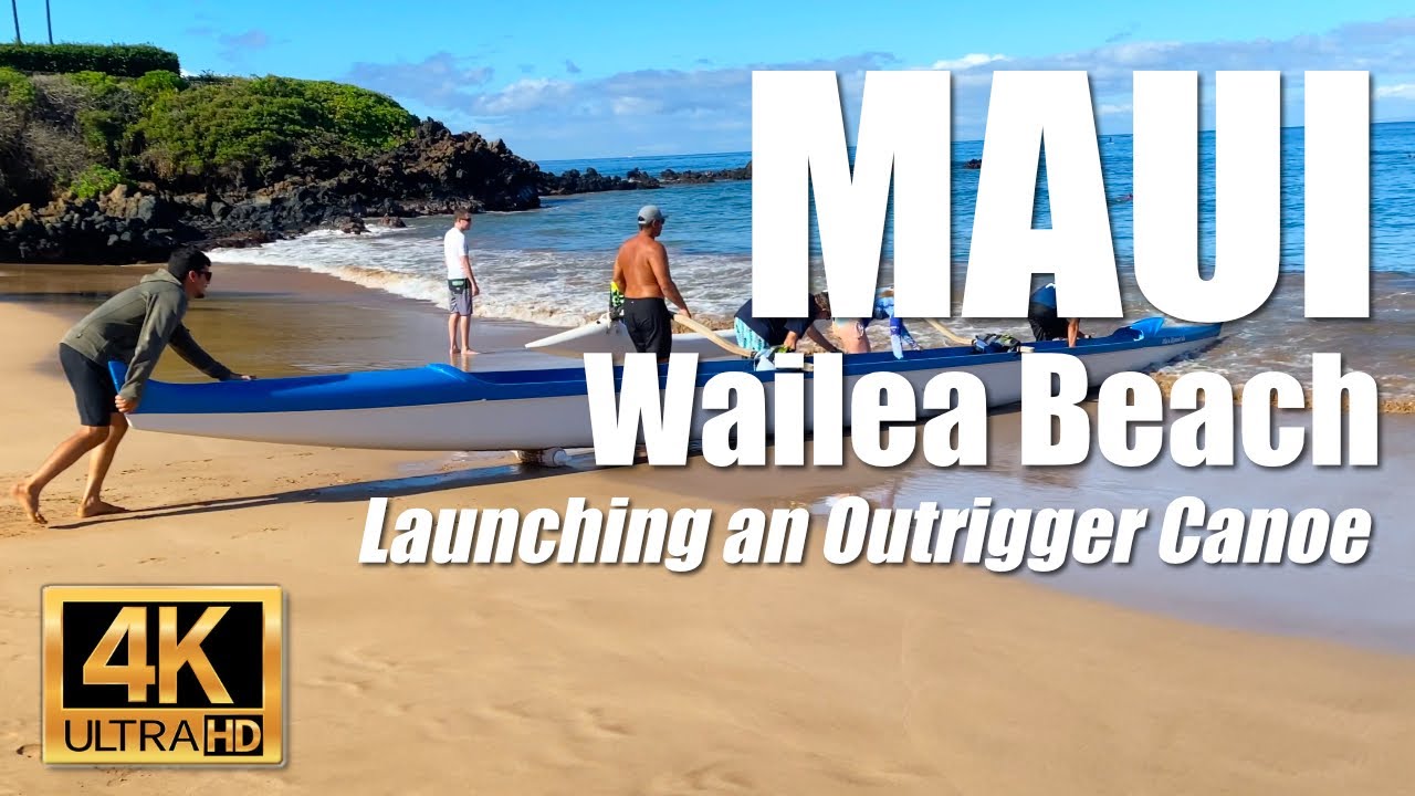 Pushing an outrigger canoe off the beach and through the surf at Wailea Beach in Maui, Hawaii  4K