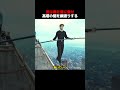 男は棒を肩に乗せ、高塔の間を綱渡りする！