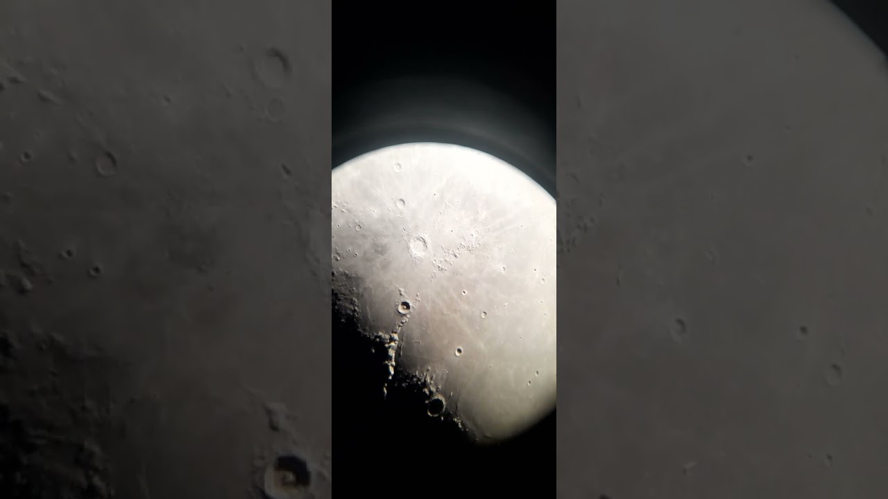 Mountains and a big crater on the moon through a telescope   