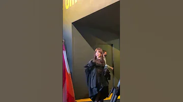 Jenna Ortega waving at a fan who's holding the lesbian flag