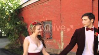 Bride and Groom Walking Along a Brick Red Wall