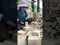 Cutting natural stone blocks manually into smaller bricks using a hammer and chisel outdoors