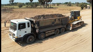 A construction site where a SHANTUI Bulldozer DH17 C3 is being used to help push dump trucks stuck