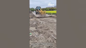 Road construction with concrete slabs: loader placing concrete slabs on a muddy road