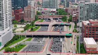 Urban highway intersection with multi lane traffic and elevated train passing between tall downtown