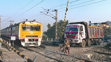 Speedy EMU local trains passing through a busy Level crossing gate