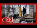 Man jumps on top of moving armored Russian vehicle while waving Ukrainian flag