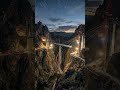 Cinematic canyon bridge build with long-exposure light trails, twin pylons, and tunnel portals.