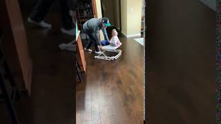 Dad pushes baby on walker but baby falls off and bumps her head on the floor it