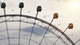 Close-up of a modern Ferris wheel with passenger cabins against a cloudy sky with warm sunset light.