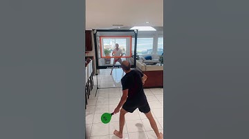 Two people are playing Jazzminton, an indoor paddle game with a net between them!