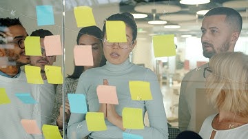Business people working with sticky notes in office using glass board talking