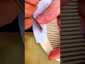carving beautiful pattern on the wooden comb surface gently using sharp chisel tool inside studio