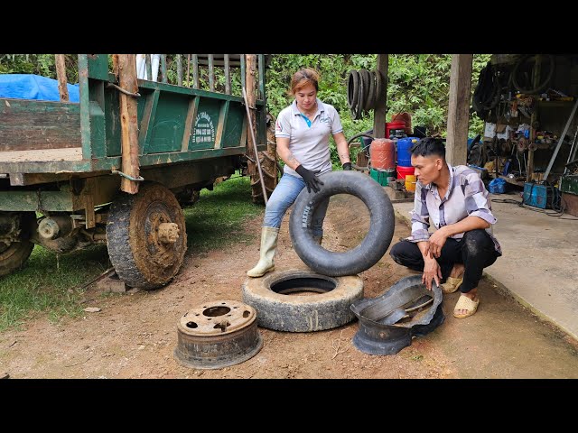 The girl mechanic helps the tractor driver fix a flat tire class=