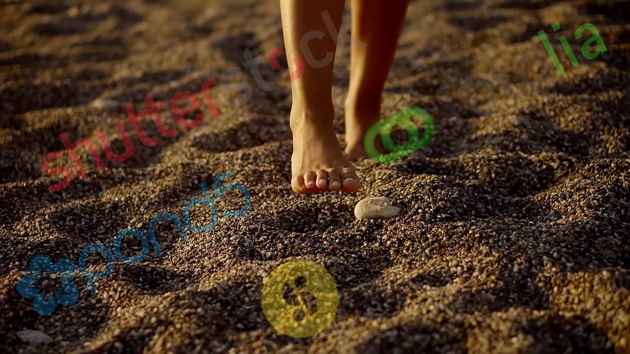 barefoot woman is walking over a coarse sand in evening time, sun is shining at an angle, close up s