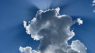 Sun rays, big puffy clouds, in the deep blue sky