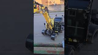 Excavator Driver Picks up a Can From a Person Sitting in a Balcony