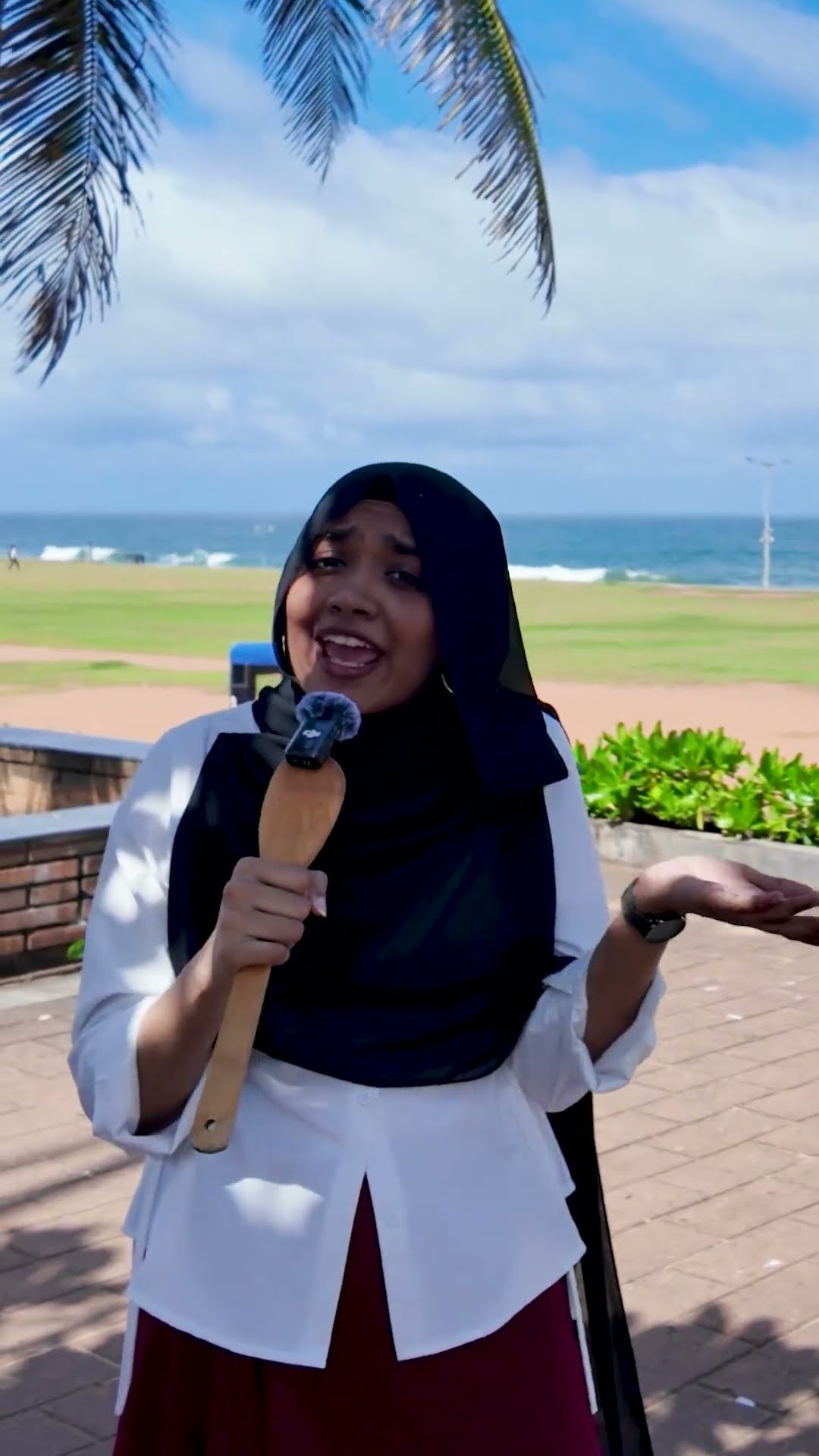 Presenter holding a microphone beside the beach