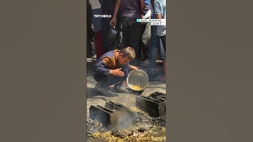 Palestinian child gathers pasta off the ground at community kitchen