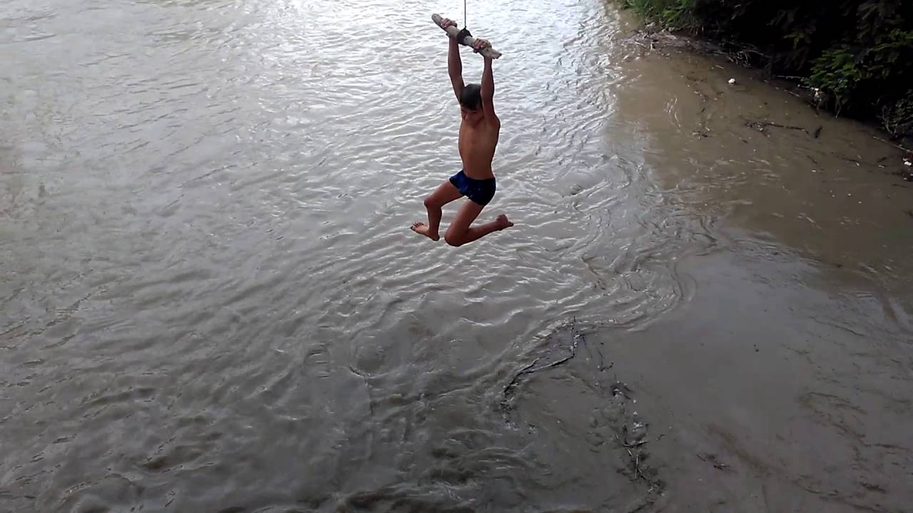 В воде ныряет в реку. Тарзанка на речке. Парень на тарзанке. Ныряет с тарзанки.