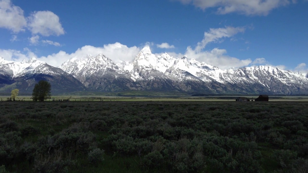 Grassland sorrounded By Mountains With Snowy Peaks